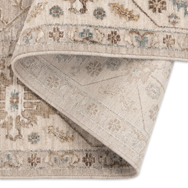 Aurelia Vintage Floral Rug in Sand folded back to show the patterned surface, stitched edge, and woven backing.