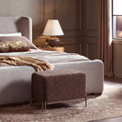 Aurelie Linen Accent Stool in brown styled at the foot of a bed in a warm contemporary bedroom.