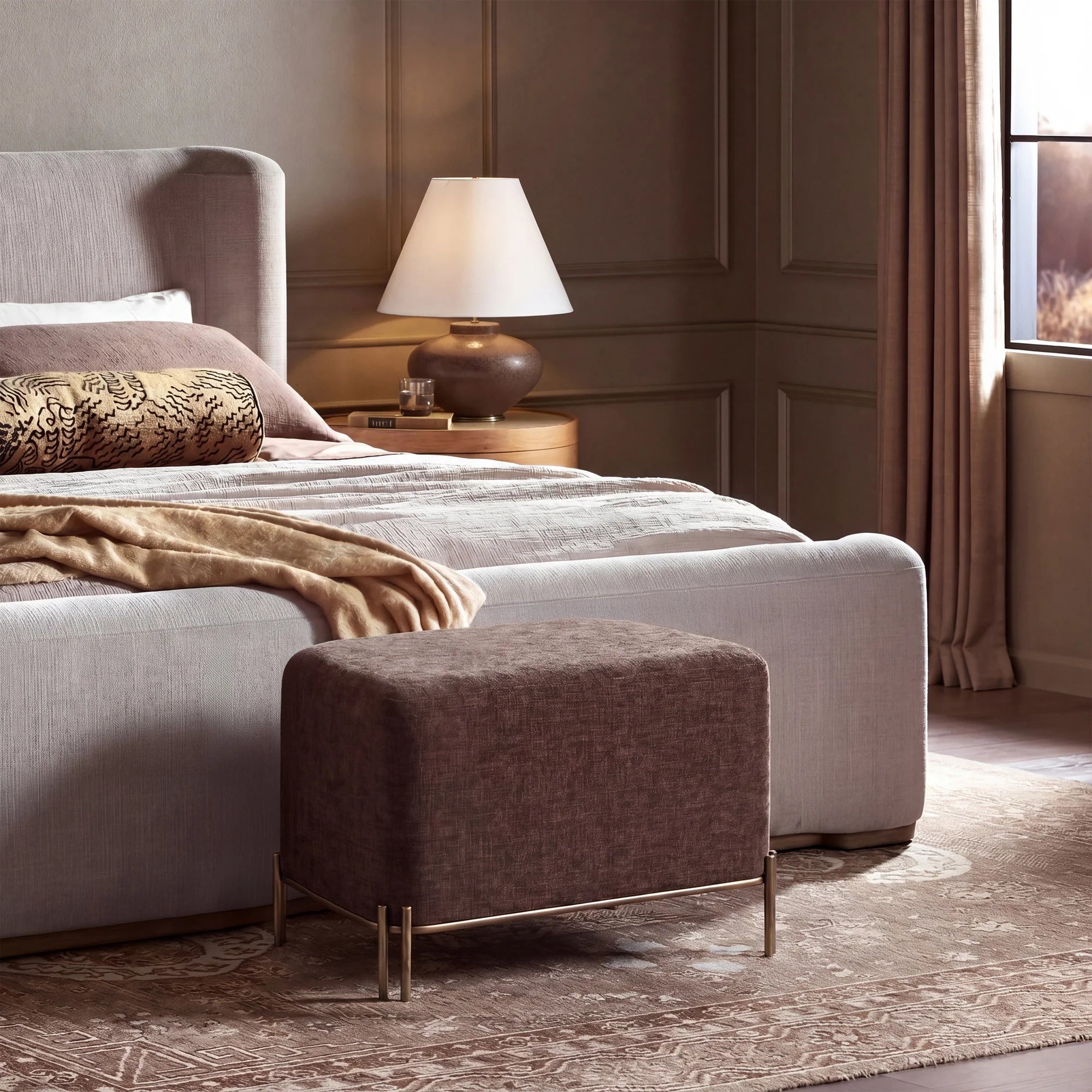 Aurelie Linen Accent Stool in brown styled at the foot of a bed in a warm contemporary bedroom.
