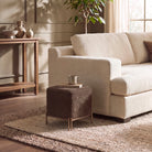 Aurelie Square Linen Accent Stool in brown styled beside a sofa in a warm contemporary living room.