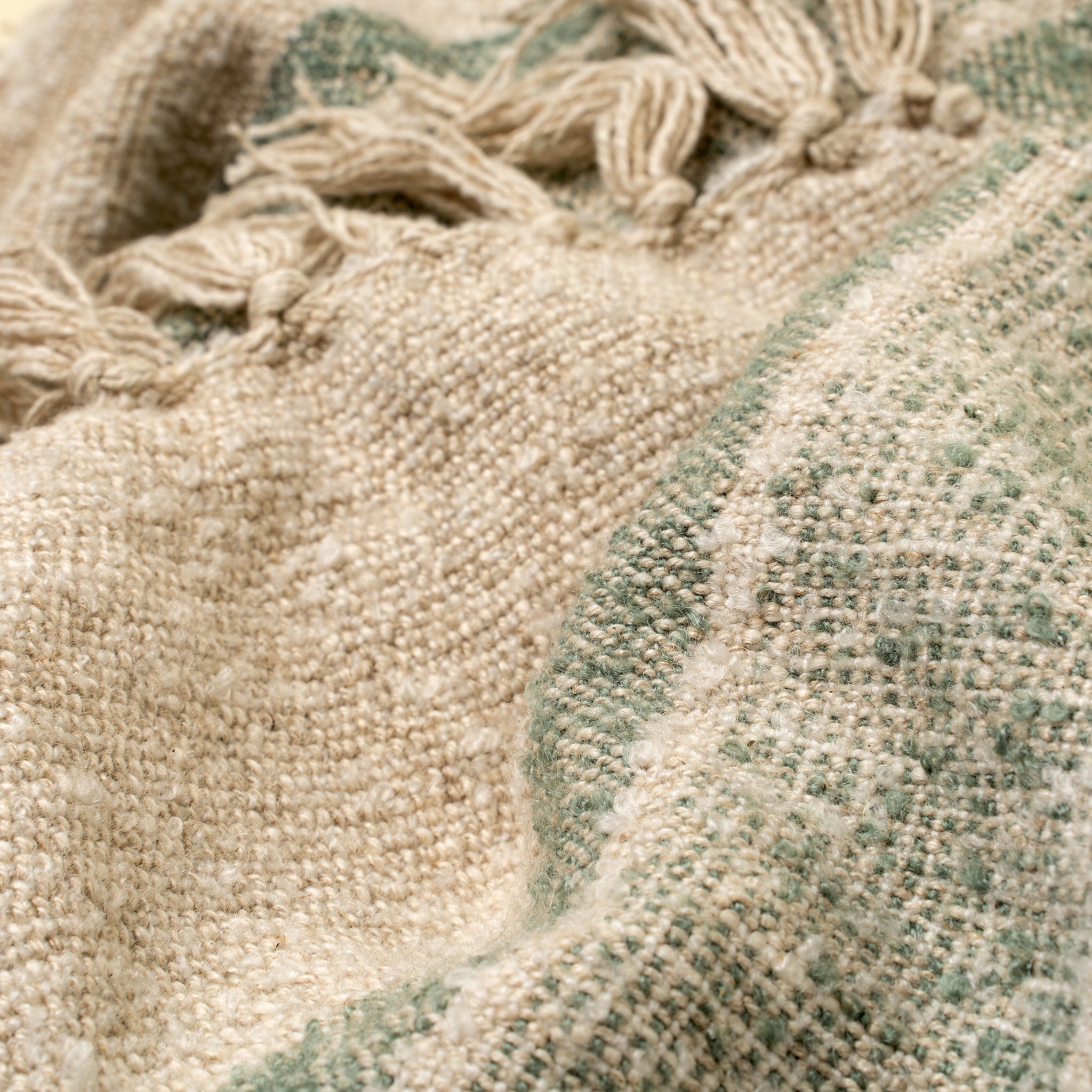 Close-up of textured fabric with tassels and a patterned border.