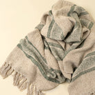 Textured scarf with green stripes and tassels on a beige background