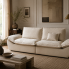 The sailing-shaped modular sofa styled in a cozy, organic modern living room with a jute rug and travertine table.