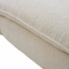 Close-up of a textured cream boucle fabric cushion and soft plush surface.