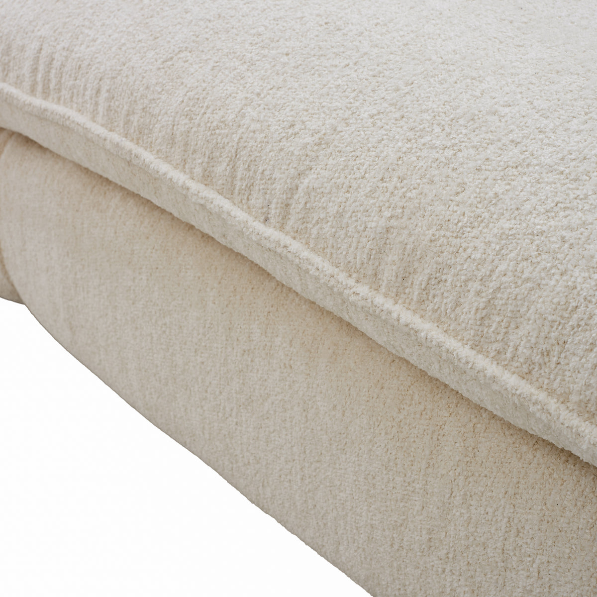 Close-up of a textured cream boucle fabric cushion and soft plush surface.