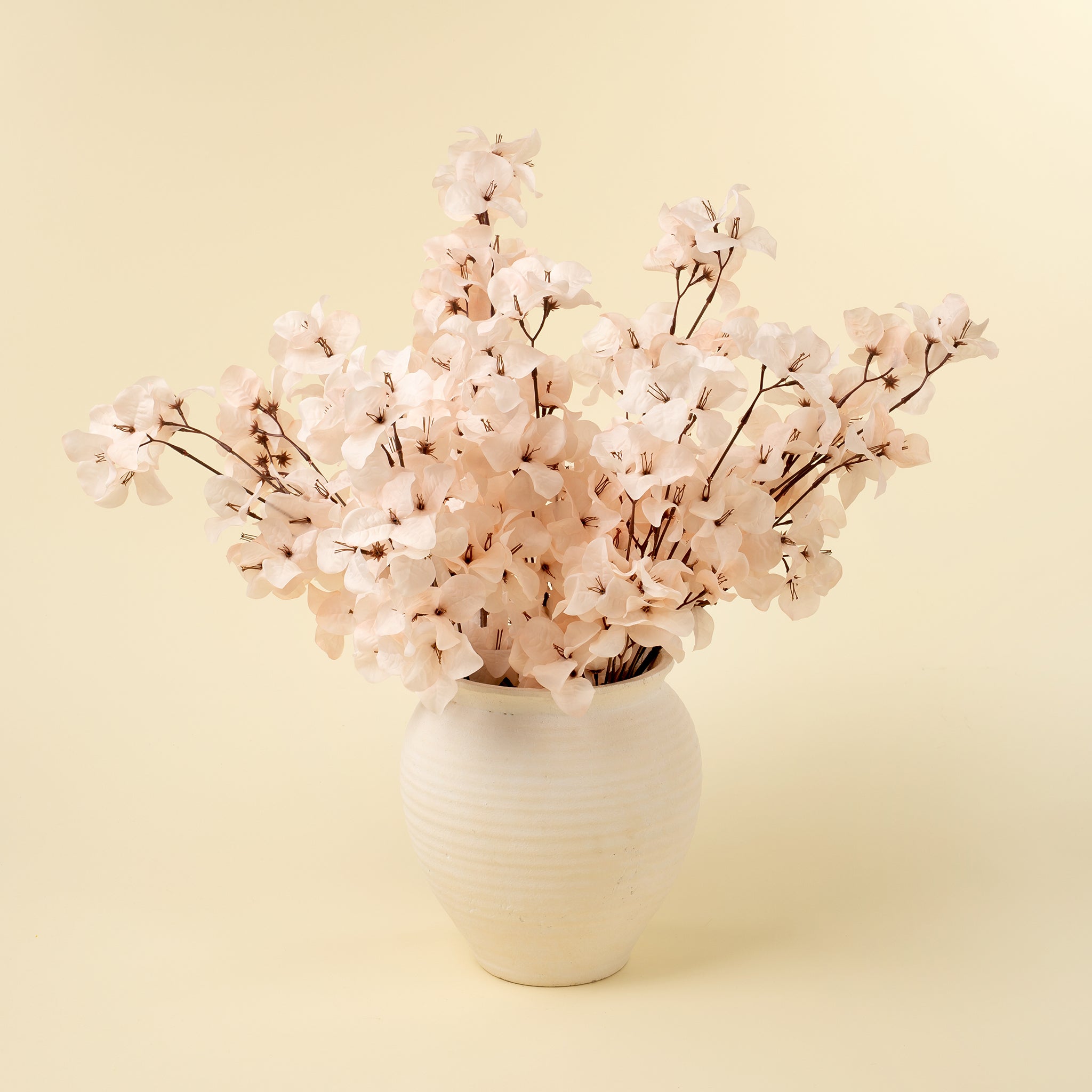 Bouquet of light pink flowers in a white vase on a light yellow background