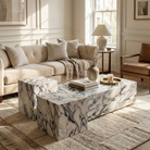 Luxury neutral living room centering a monolithic stone coffee table cluster set with dramatic grey and burgundy veining.