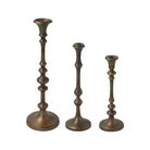 Caldria set of three antique brass-finished candle holders with sculpted stems and round bases, shown without candles.