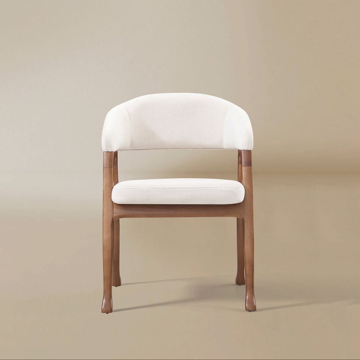 Front view of the Calira linen dining chair showing its wraparound backrest, integrated arms and rounded upholstered seat