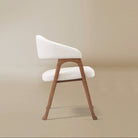 Side profile of the Calira linen dining chair showing its sloping upholstered arm, open frame and subtly flared feet