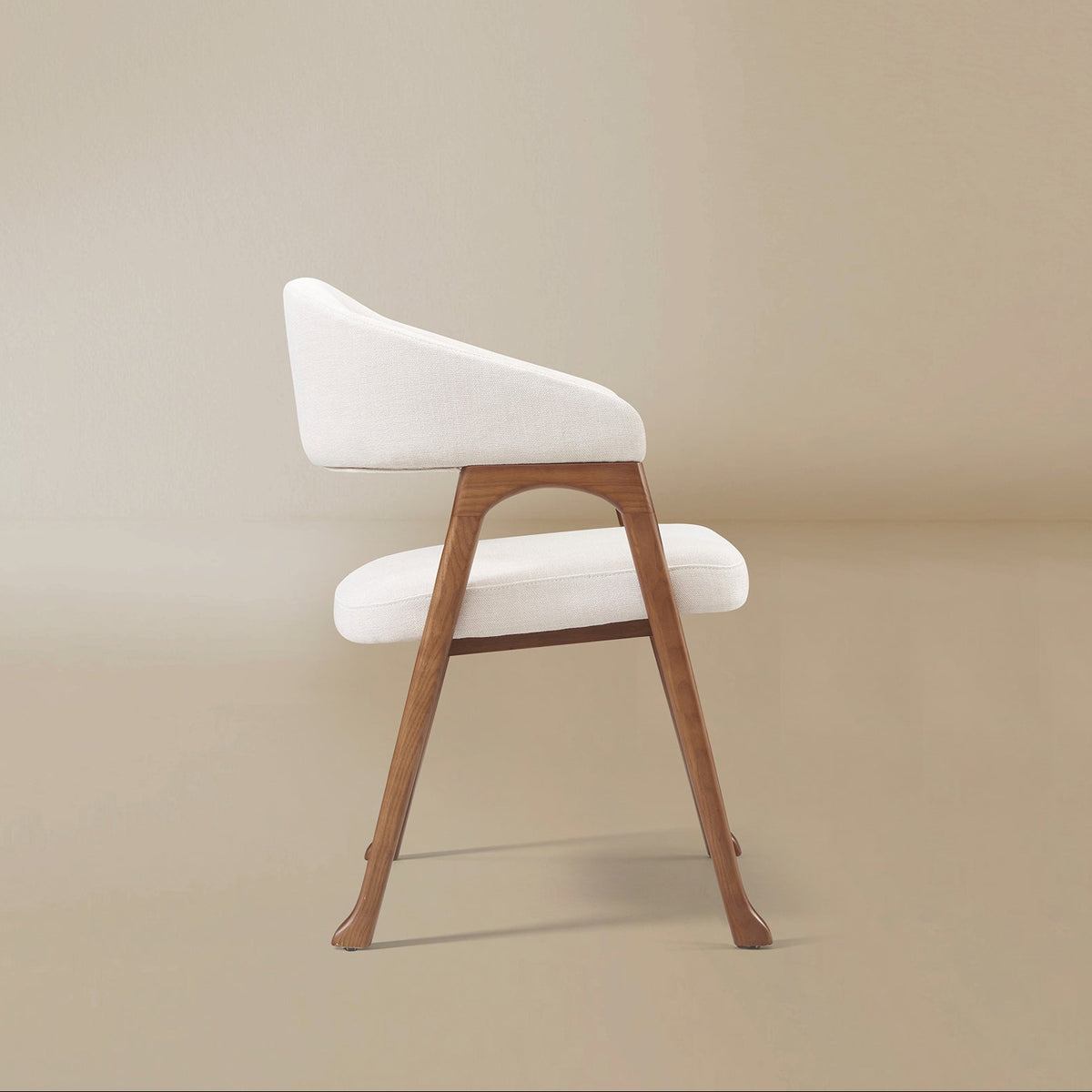 Side profile of the Calira linen dining chair showing its sloping upholstered arm, open frame and subtly flared feet