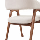 Close-up of the Calira linen dining chair showing its padded seat, wood frame and flared leg detail