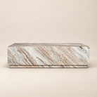 Front studio view of the Calista Marble Plinth Coffee Table with warm cream and rust-toned natural marble veining on a beige background.