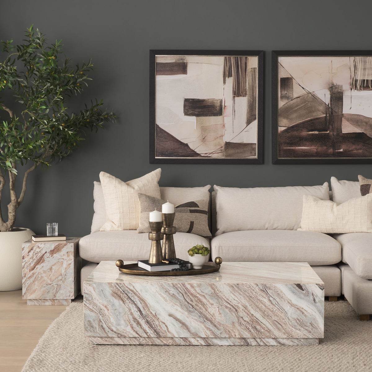 Close lifestyle view of the Calista Marble Plinth Side Table beside a cream sofa, showing its polished marble surface and compact square form.