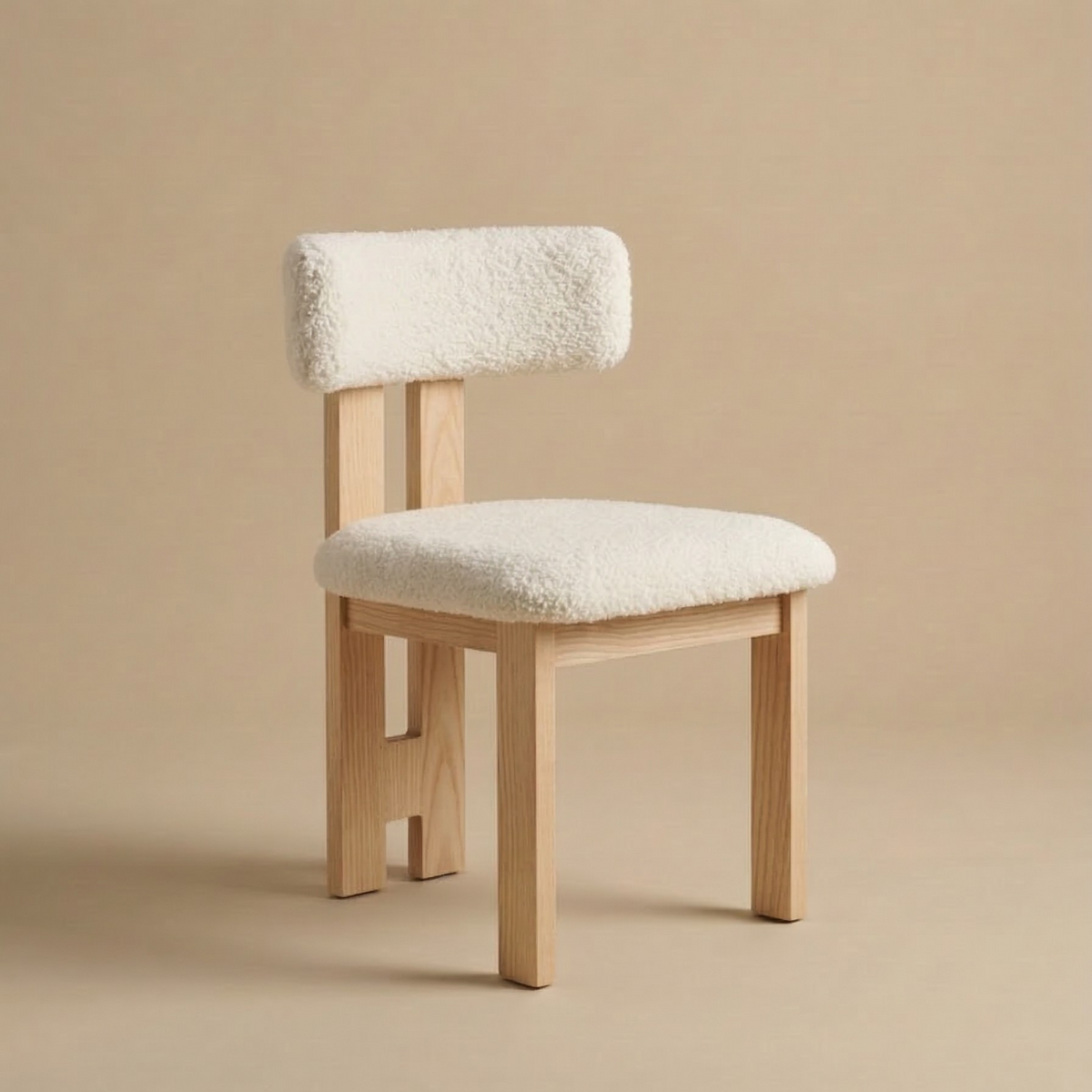 Angled view of the bouclé dining chair showing its curved backrest, plush white textured upholstery, and natural light wood legs featuring the Casper Bouclé...