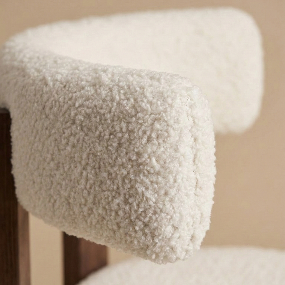 Close-up detail of the modern dining chair showing the contrast between the soft white nubby bouclé fabric and the smooth dark ash wood frame featuring the...