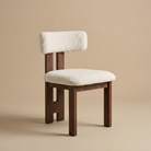 Angled view of the bouclé dining chair showing its curved backrest, plush white textured upholstery, and dark ash wood legs featuring the Casper Bouclé...
