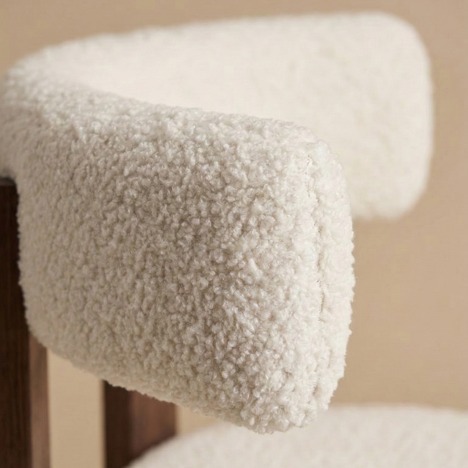 Close-up detail of the modern dining chair showcasing the contrast between the soft white nubby bouclé fabric and the smooth dark ash wood frame.