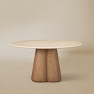 Caspia Botticino marble round dining table on a warm beige studio background