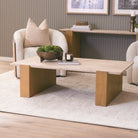 Cavelle Travertine & Oak Coffee Table styled in a warm contemporary living room with two lounge chairs.