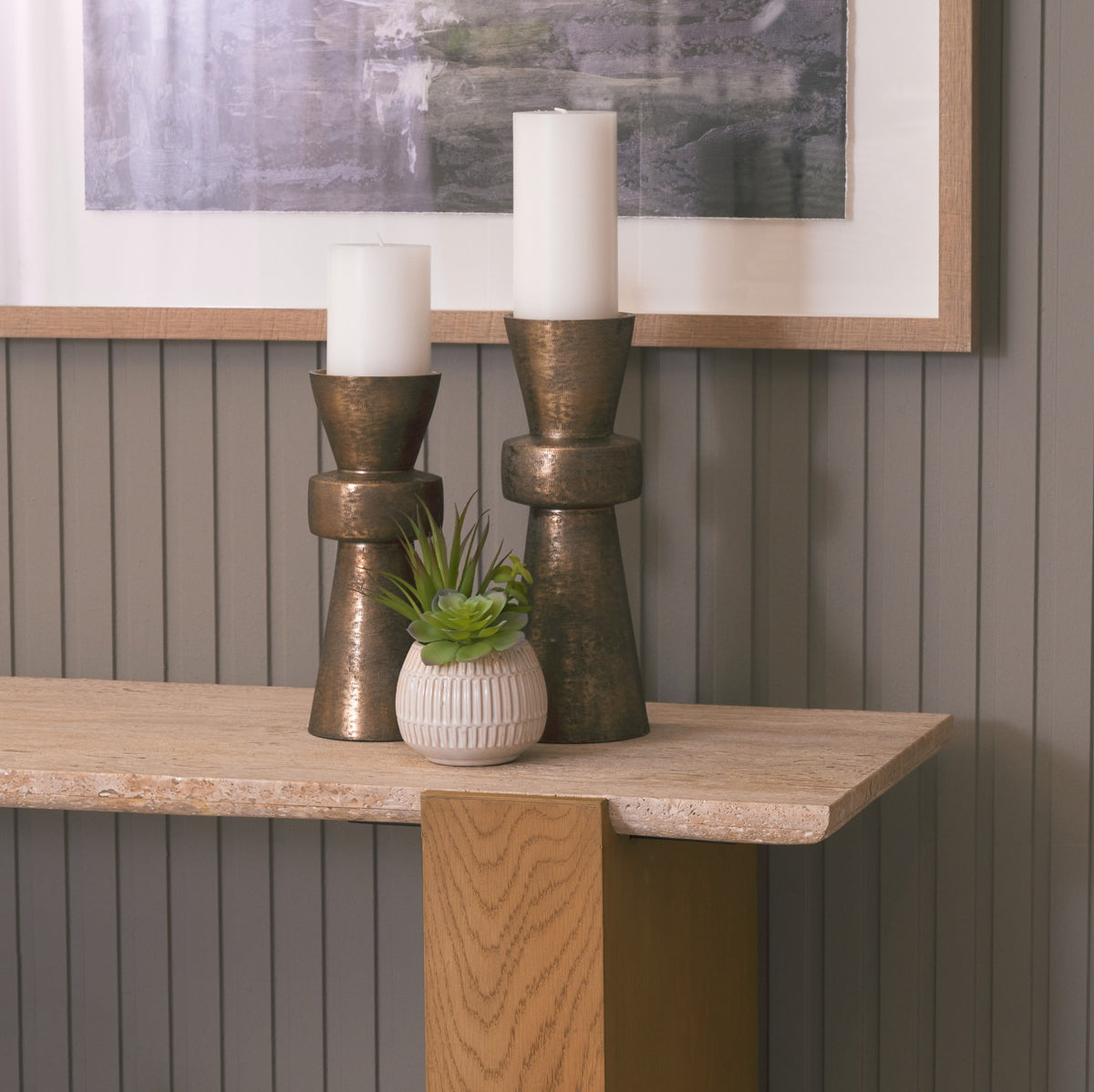 Lifestyle detail of the Cavelle Travertine & Oak Console Table with candles and a small planter arranged on the travertine surface.