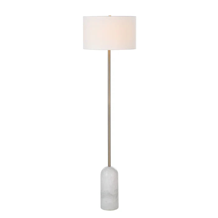 Lit view of the Celine floor lamp casting a soft warm glow through its white linen drum shade, highlighting the brass stem.
