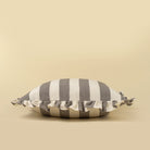 Striped pillow with ruffle trim on a beige background