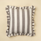 Striped pillow with ruffle trim on a beige background