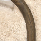 Close-up detail of the Coco chair's arched armrest showcasing the smooth dark walnut wood grain against the shaggy sand fur.