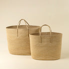 Two woven baskets with handles on a beige background