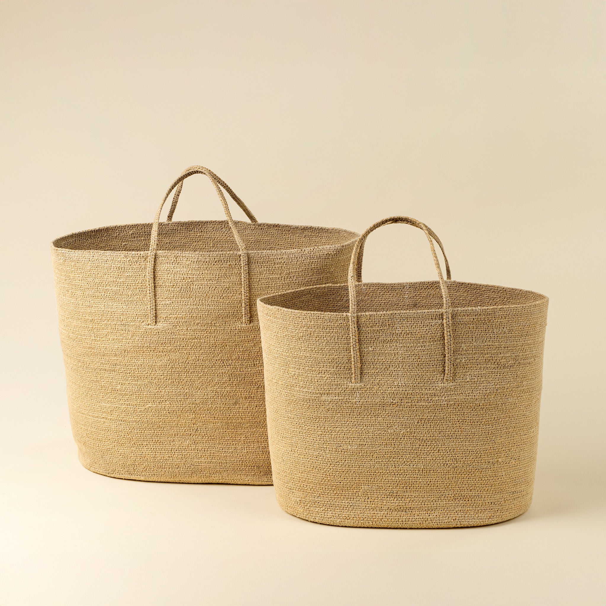 Two woven baskets with handles on a beige background