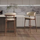 Two curved back linen and ash wood counter stools styled at a modern kitchen island with a stunning marble backsplash.