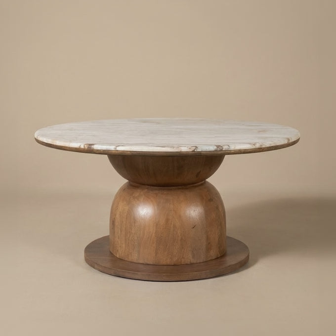 Front view of the Ottille round coffee table with marble top and wooden base on a beige studio background
