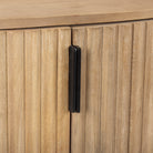 Macro detail of the textured fluted doors and matte black vertical hardware on the light wood Eleanor cabinet.