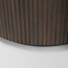 Close-up of the curved bottom edge and vertical fluted wood detailing on the dark brown Eleanor accent cabinet.