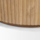 Close-up of the curved bottom edge and vertical fluted wood detailing on the light natural Eleanor accent cabinet.
