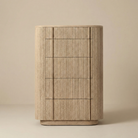 Front view of the Elias tall chest of drawers in natural oak, featuring a curved silhouette and five deep drawers with ribbed wood detail.