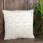 Textured white pillow on a wooden surface with a wooden wall and plant in the background