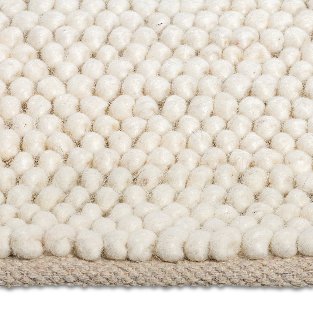 Macro close-up of the soft, pebble-like knotted texture of the cream Felix handmade rug