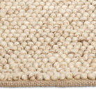 Macro close-up of the soft, pebble-like knotted texture of the beige Felix handmade rug.