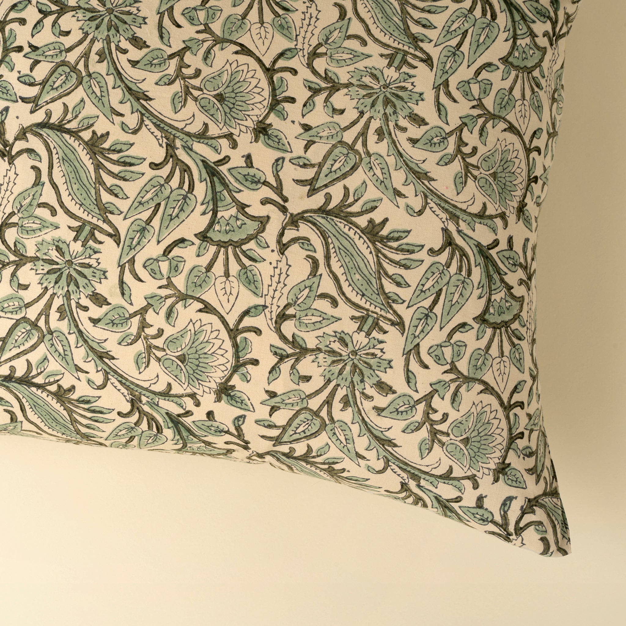 Decorative pillow with green floral pattern on beige background