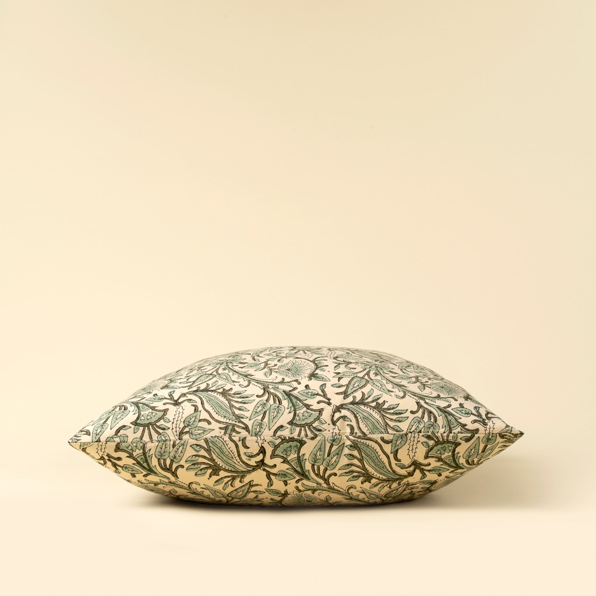 Decorative pillow with green leaf pattern on a beige background