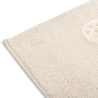 Folded corner of the Flutterby Meadow Kids Rug showing soft butterfly details and the woven backing.