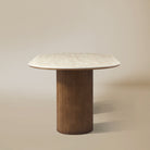 Wood base side view of the Gianna dining table with oval top and dual wood pedestal base on beige studio background