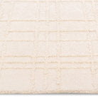 Macro close-up of the raised tufted geometric grid pattern and soft cream pile on the Hayes textured area rug.