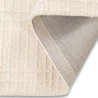 Folded corner of the neutral Hayes textured grid rug showing the underside woven backing construction