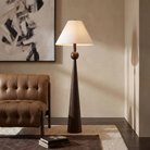 Inez Dark Walnut Floor Lamp styled beside a brown leather chair in a warm contemporary living room.