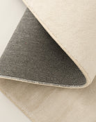 Folded corner of the Isabella Rug showing the cream pile, bound edge and dark woven backing