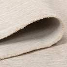 Folded edge of the Jeanne Rug showing its soft low pile and woven backing