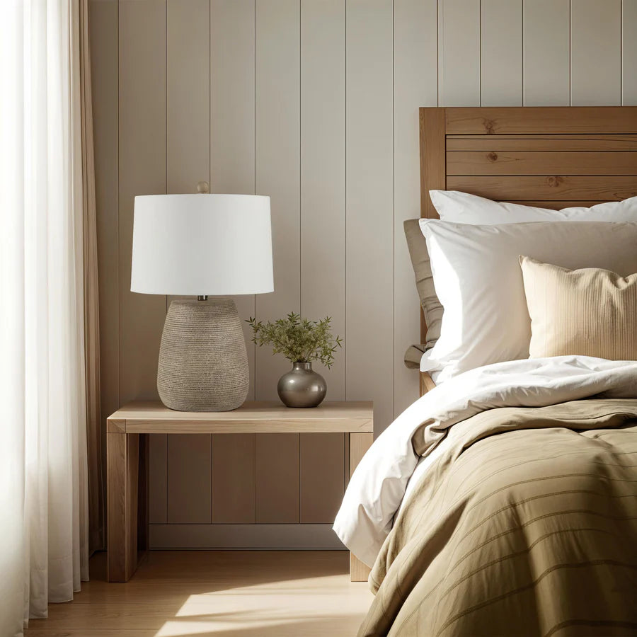 Bedroom with wooden headboard, nightstand with lamp, and light-colored walls.